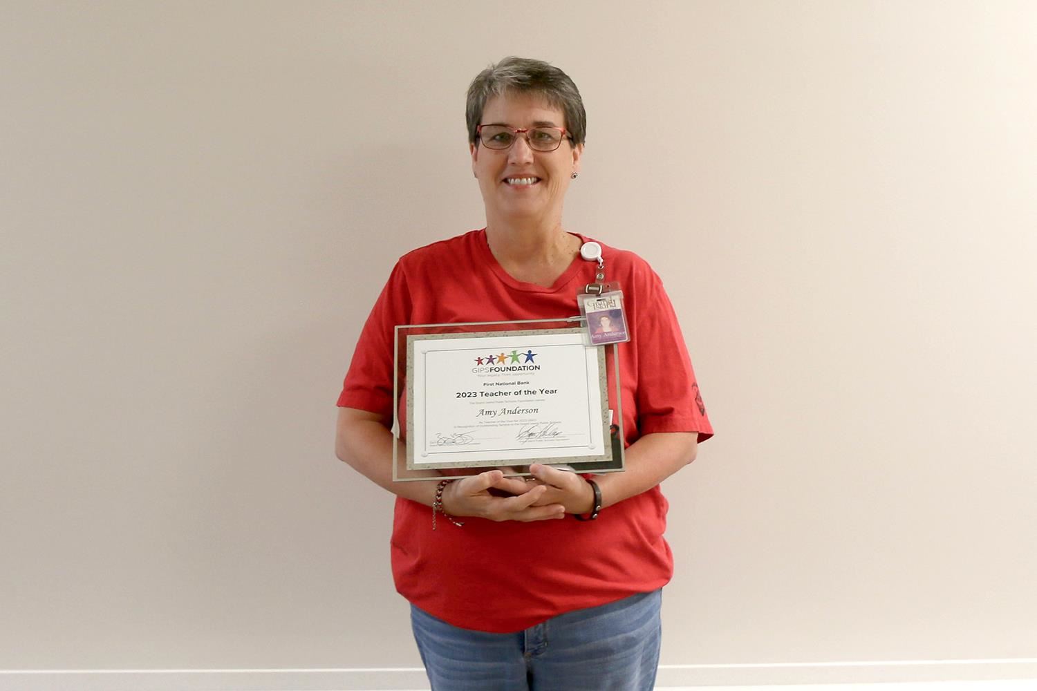 Amy Anderson smiling and standing with her Elementary Teacher of the Year plaque